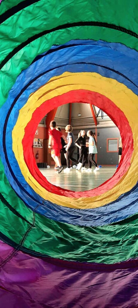 groupe d'enfants qui joue au handball adapté vu à travers un tunnel de jeu
