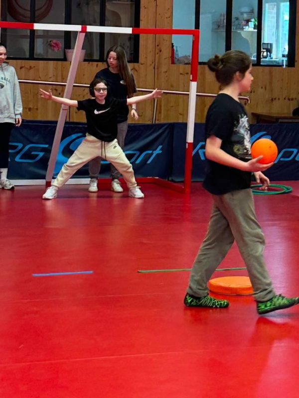 jeune garçon avec un casque pour réduire le bruit dans un but de handball et une fille qui va tirer